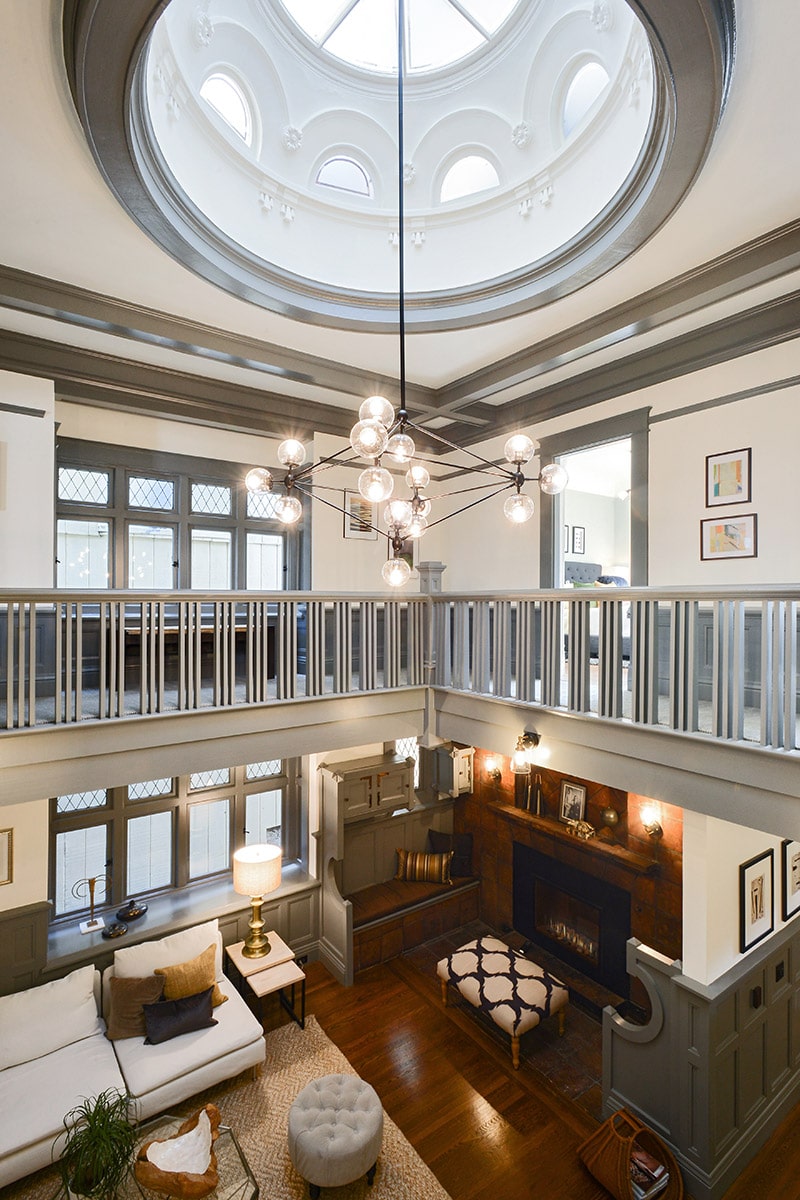 Two-story living room with a large circular skylight dome and modern globe chandelier.